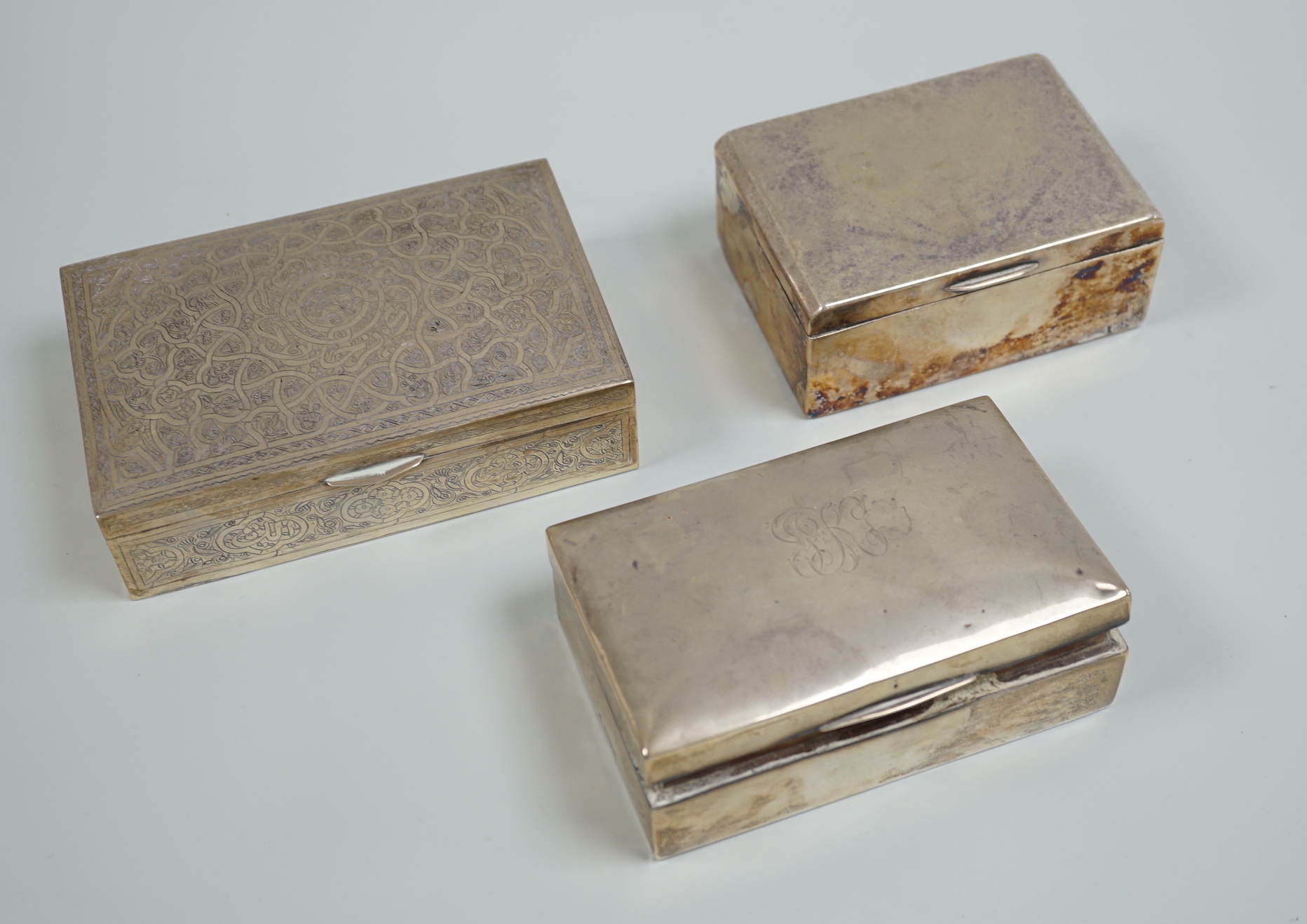 A George V silver mounted cigarette box, 13.9cm, a Persian engraved white metal cigarette box and one other cigarette box.